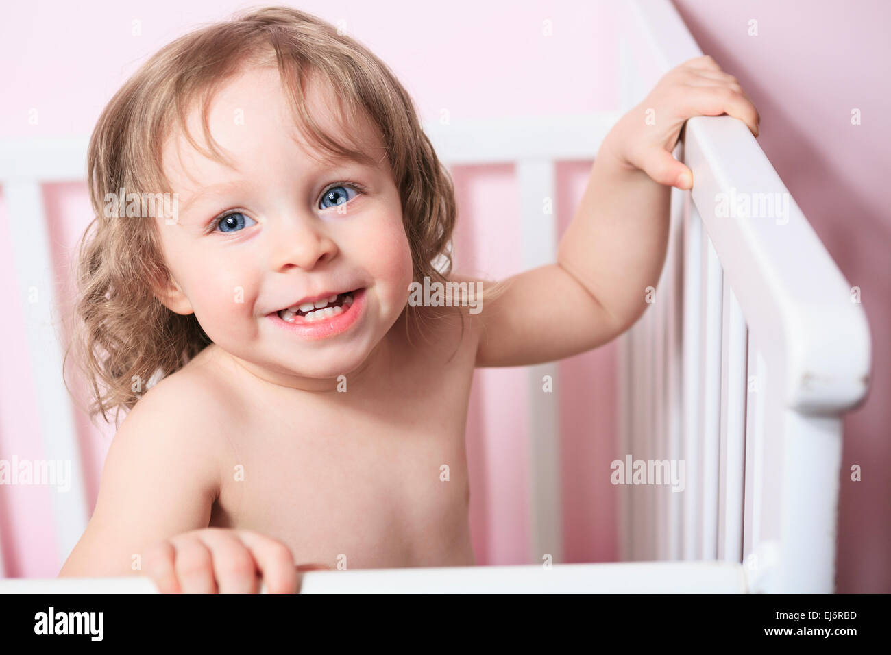 A baby in his crib with pink background Stock Photo