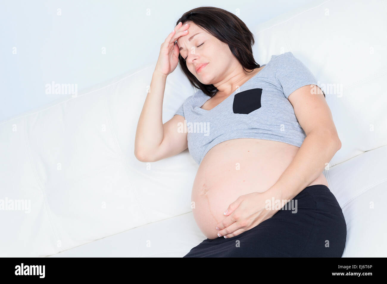 Struggling with morning sickness. Depressed pregnant woman holdi Stock Photo