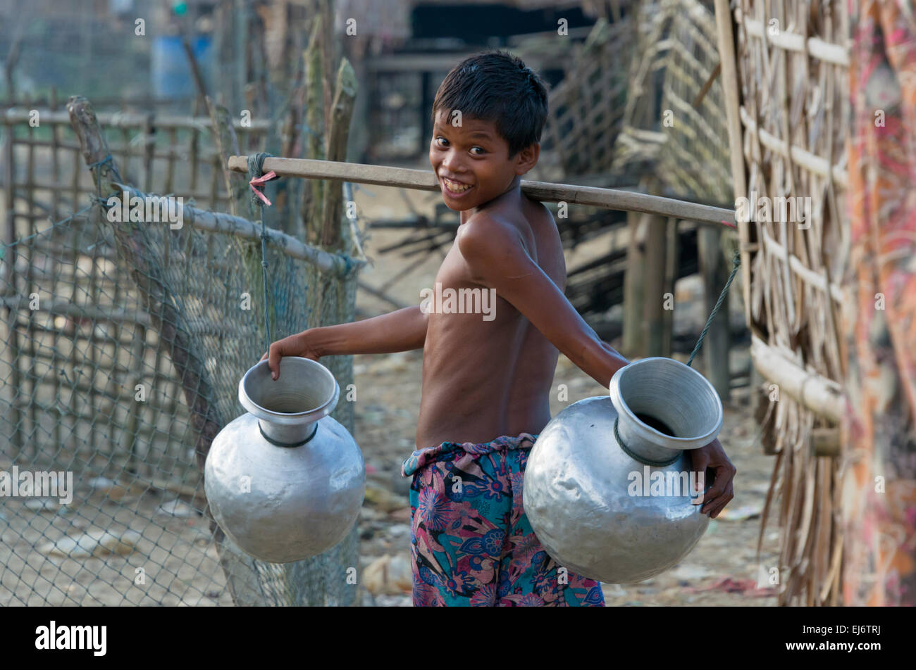 Boy carrying water jars with a shoulder pole in the fishing village, Sittwe, Rakhine State, Myanmar Stock Photo