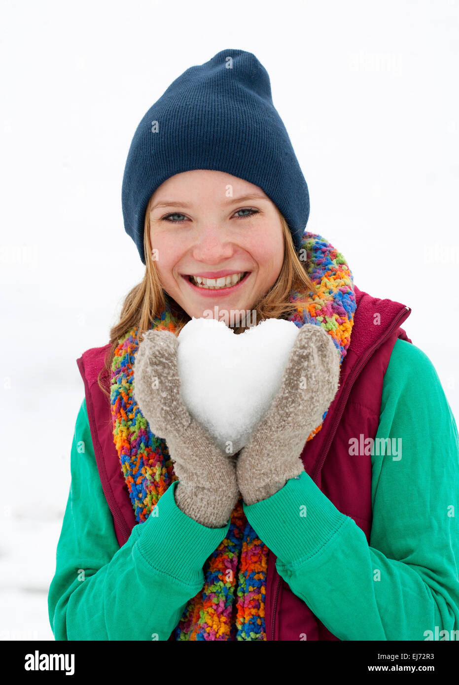 Young woman, 22 years, holding a heart made of snow Stock Photo