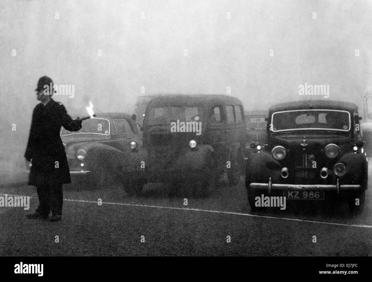 Policeman on point duty seen here using flares to guide the traffic during a heavy smog in London. 8th December 1952 Stock Photo