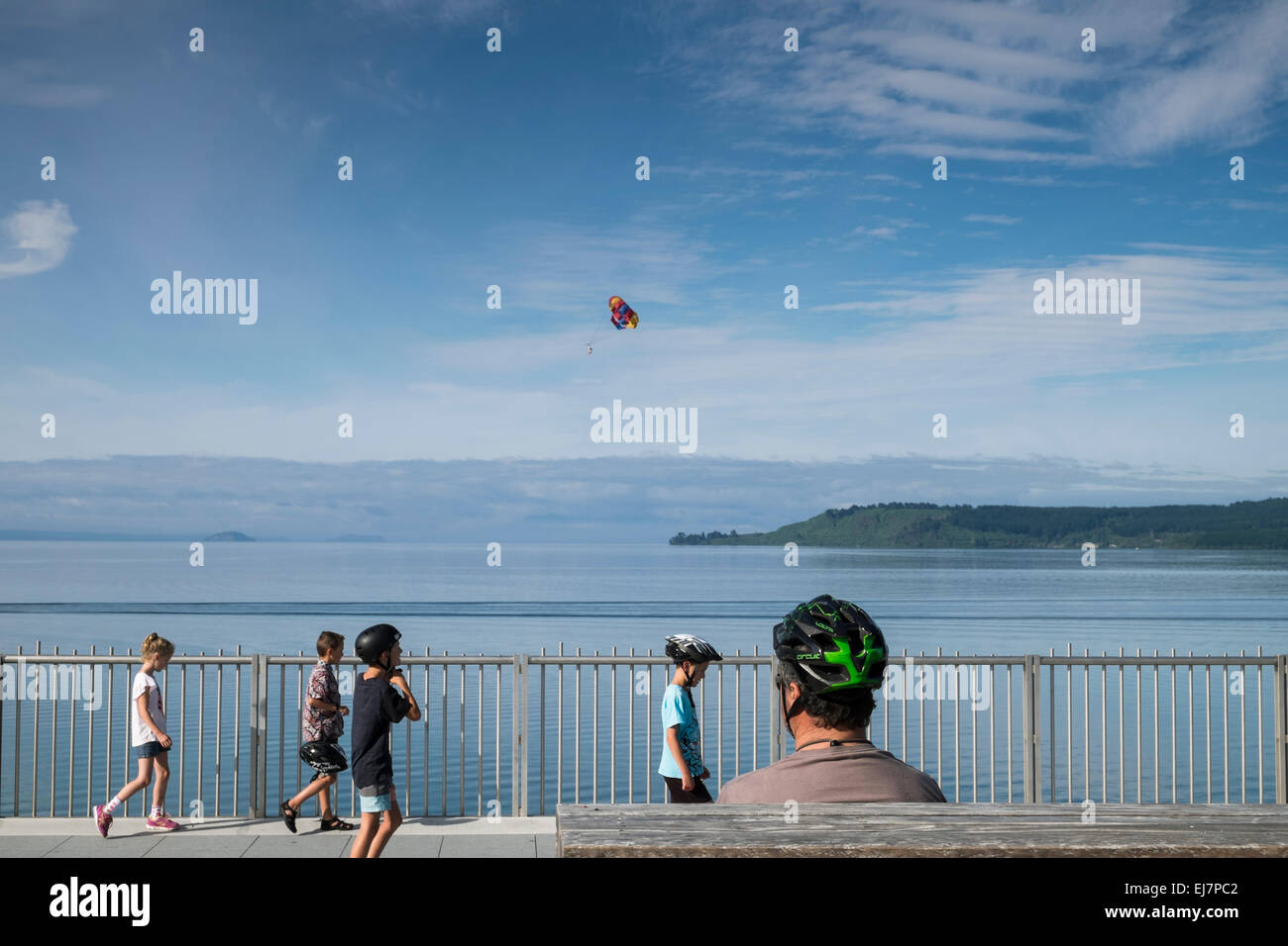 Man with children wearing cycle safety helmets along the walkway next to Lake Taupo, New Zealand. Stock Photo