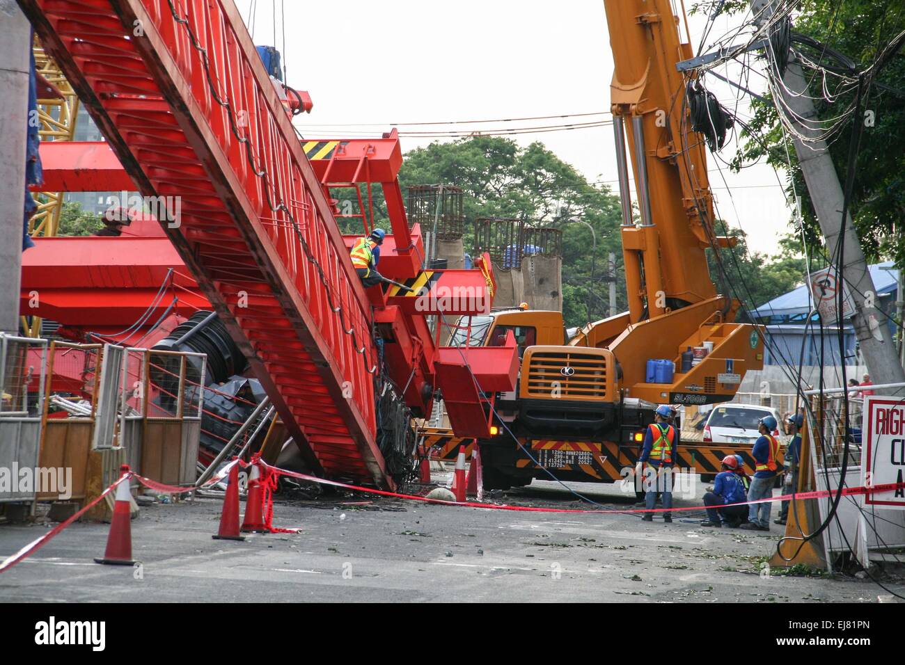 Pasay, Philippines. 23rd Mar, 2015. Workers try to secure the collapsed girder launcher before they dismantle and remove it by heavy lift cranes. At around 3 in the afternoon today along Andew's Avenue near Tramo in Pasay City, a girder launcher, from the on-going construction of the NAIA expressway, collapsed causing damages to passing cars. No reports of casualties but the incident damaged at least 5 cars and caused heavy traffic along Andrew's Avenue. Credit:  J Gerard Seguia/Pacific Press/Alamy Live News Stock Photo