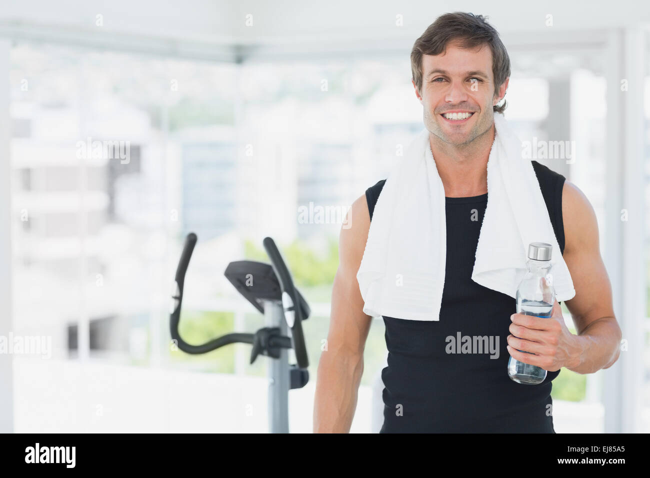 Smiling man holding water bottle at spinning class in bright gym Stock ...
