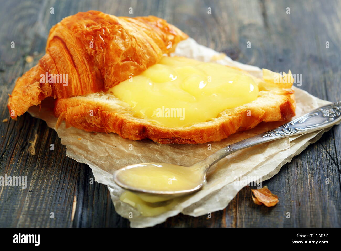 Croissant with cream and teaspoon. Stock Photo