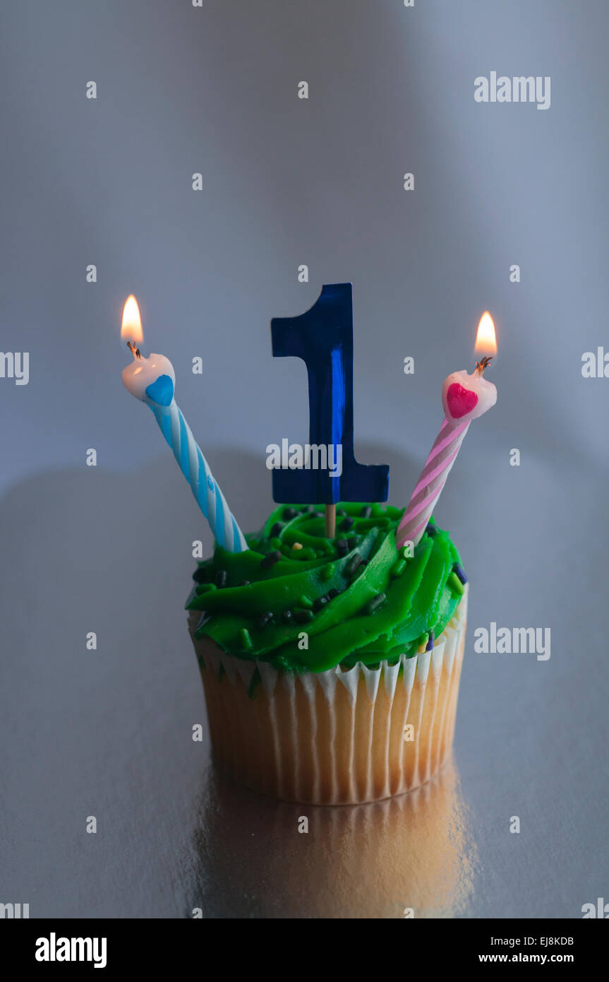 Blue number one in cupcake with two burning candles Stock Photo