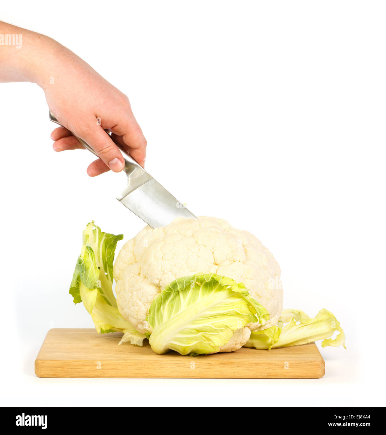 Hand cuts with a knife through a cauliflower on wooden cutting board Stock Photo