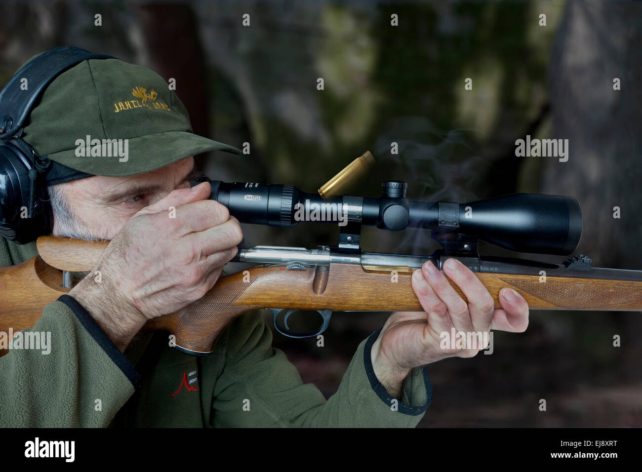 Elderly hunter with mauser bolt action riffle that kicks out empty bullet casing while repeating/reloading the rifle, Stock Photo