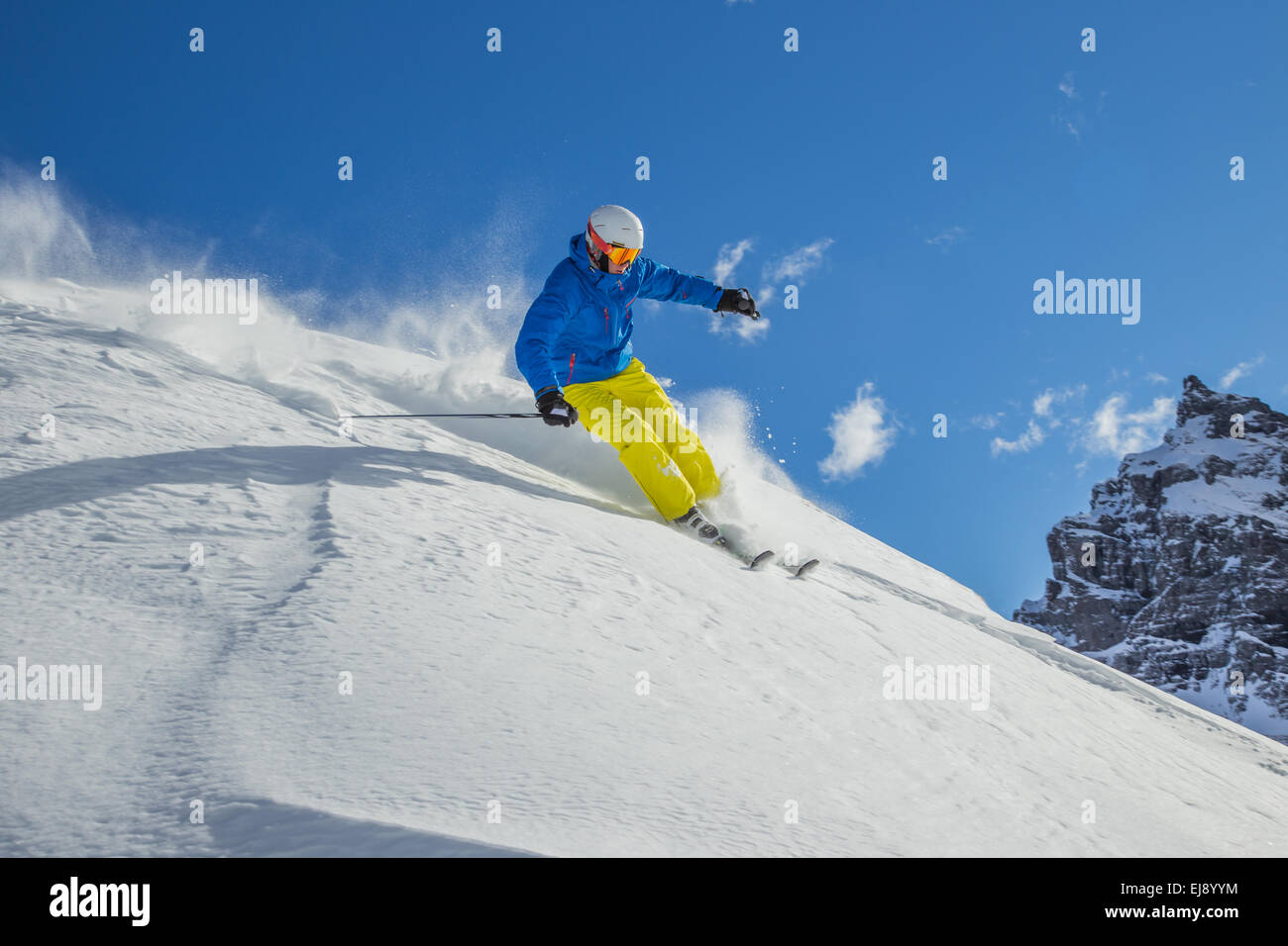 Skier skiing downhill in high mountains during sunny day. Stock Photo