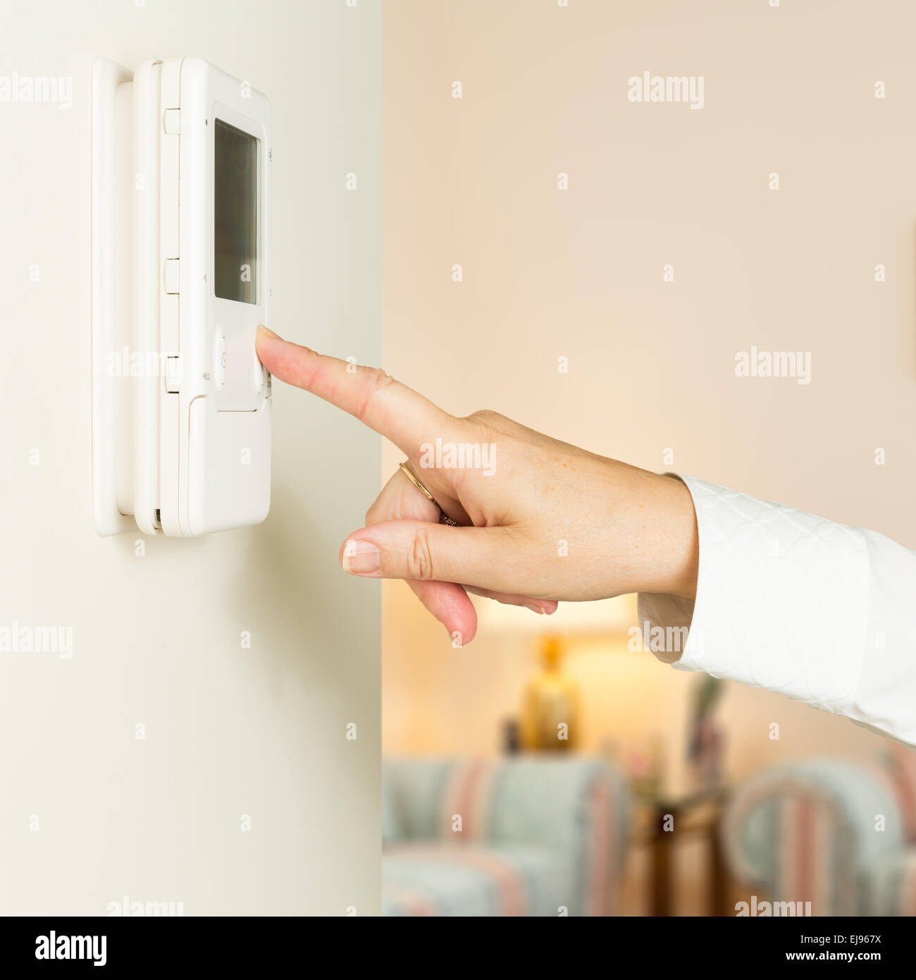 Caucasian lady pressing modern thermostat Stock Photo
