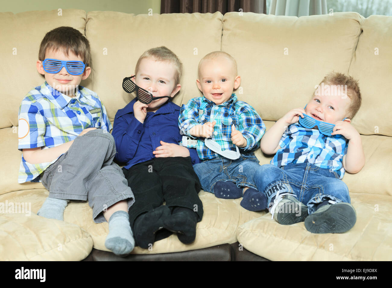 Four little kid site on the sofa Stock Photo - Alamy