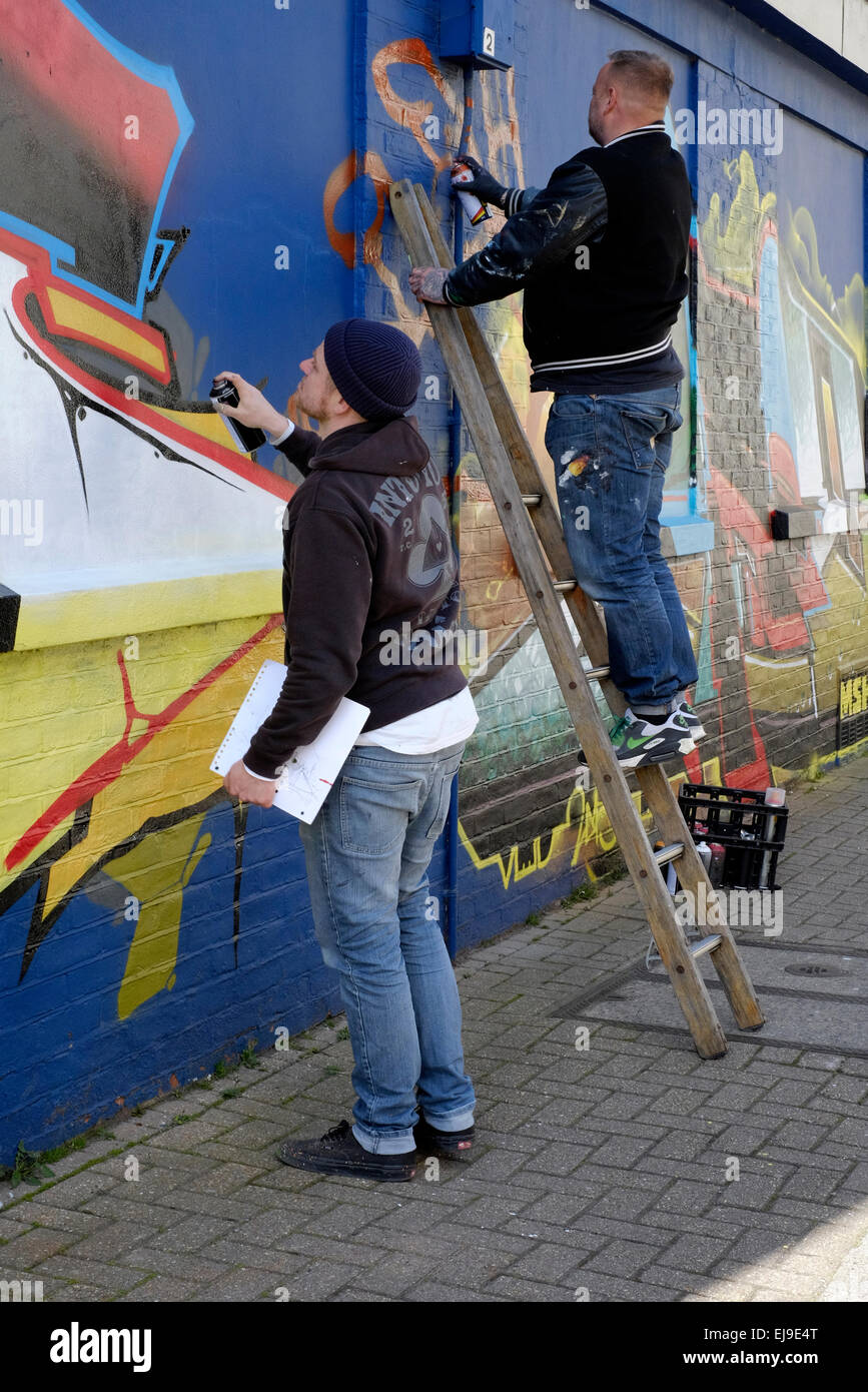 artists creating modern street art graffiti spray painted on a wall ...