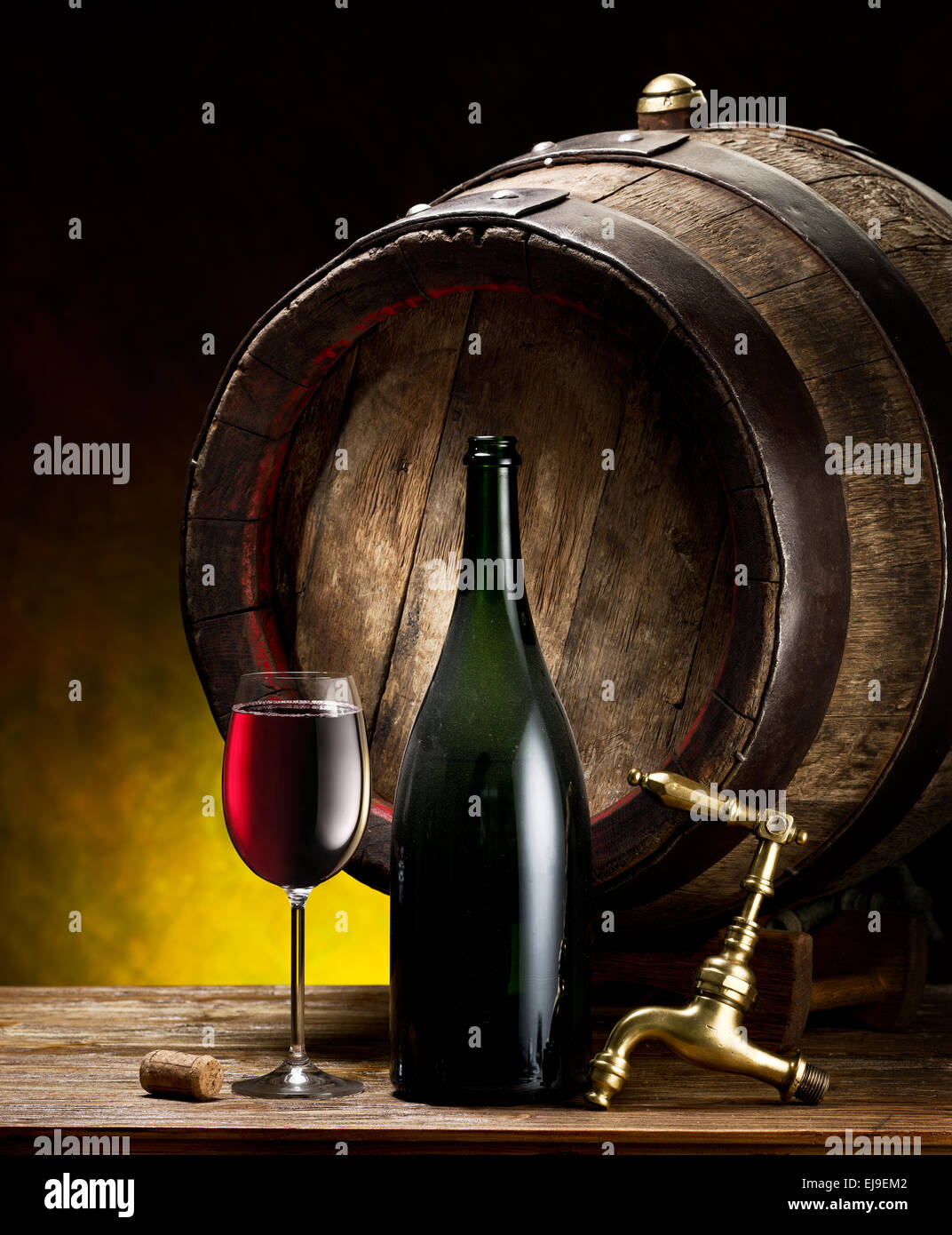 Still-life with glass of wine, bottle and barrel on the table in the cellar. Stock Photo