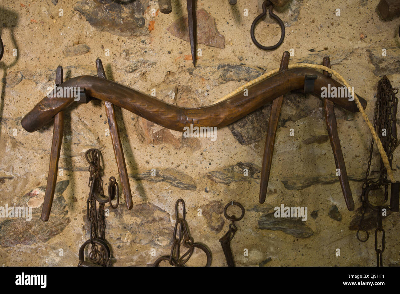 Old wooden yoke hanging on a stone wall, Badajoz, Spain Stock Photo