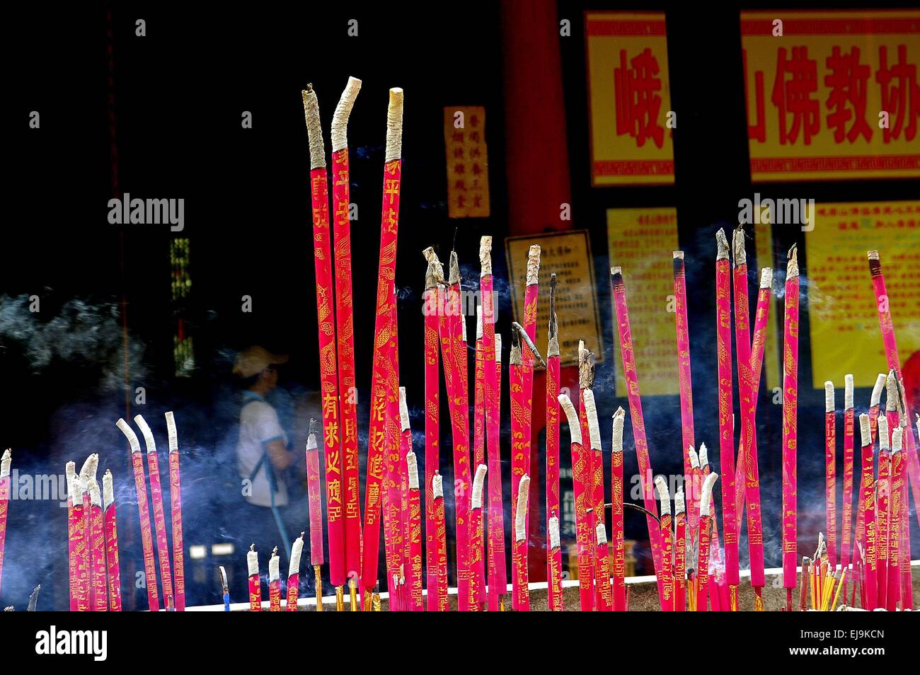 Emeishan, China:  Bright pink incense sticks burning in a brazier at the Bao Guo Buddhist Temple on Mount Emei Stock Photo