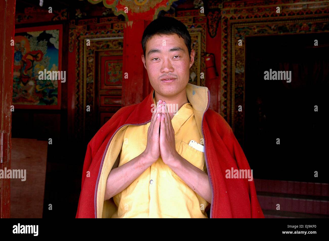 Gamel, China:  Tibetan monk with clasped hands welcomes visitors to the Gamel Chador Gonchen Temple Stock Photo