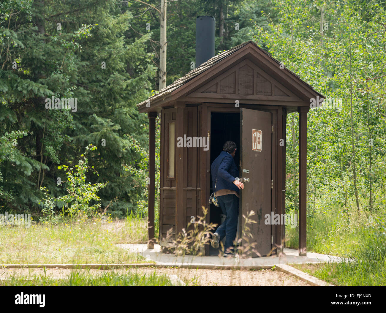 Woman entering restroom in forest Stock Photo