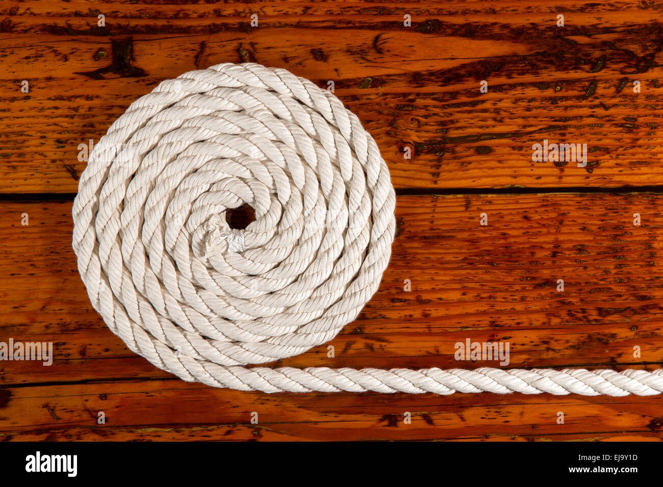 Coiled white rope on a highly textured wooden background. Nautically ...