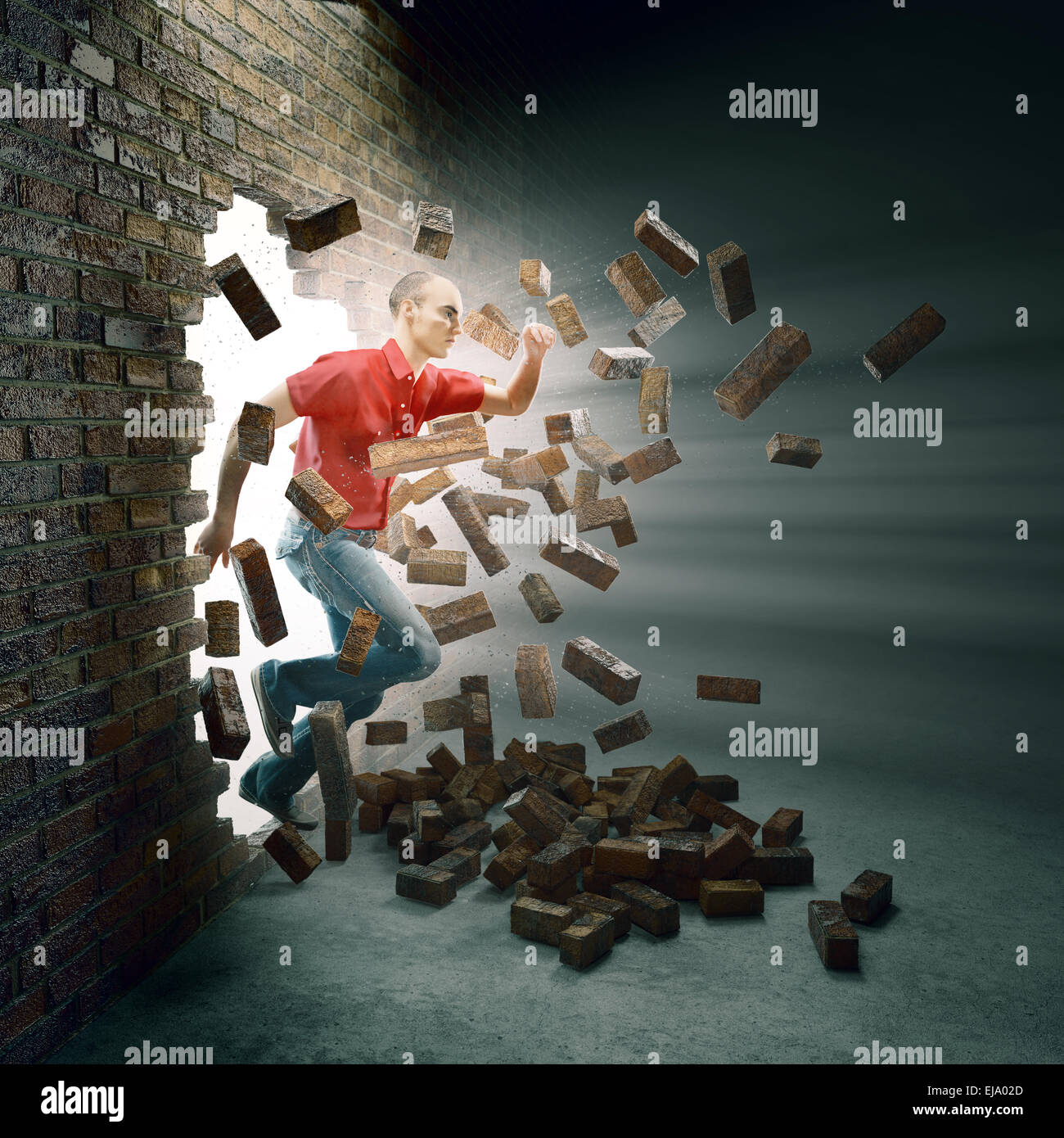 Young man running through a brick wall Stock Photo