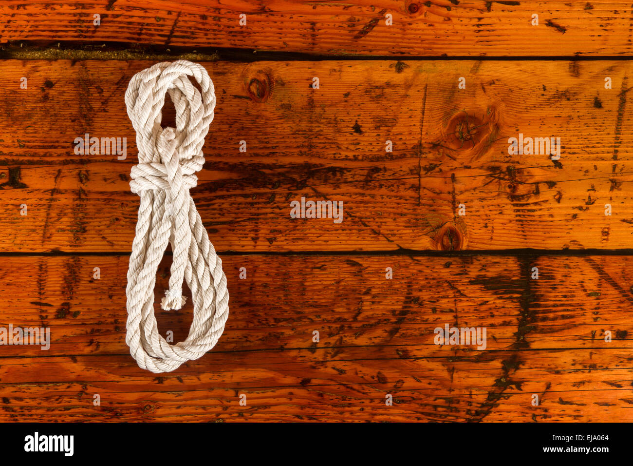 Coil of white rope on highly textured wood.  Copy space to right. Stock Photo