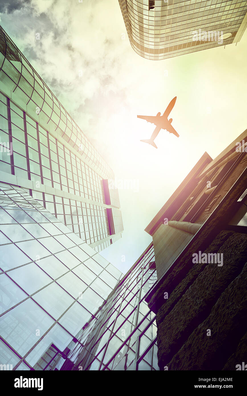 plane flying over modern office towers Stock Photo