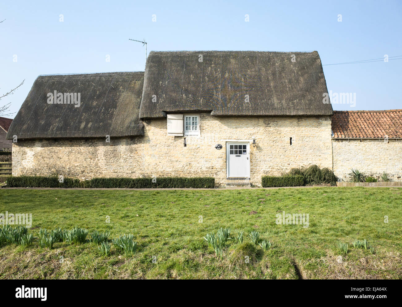 Converted from a stone barn, a house with one window and one door onthe side facing out across a green. Stock Photo