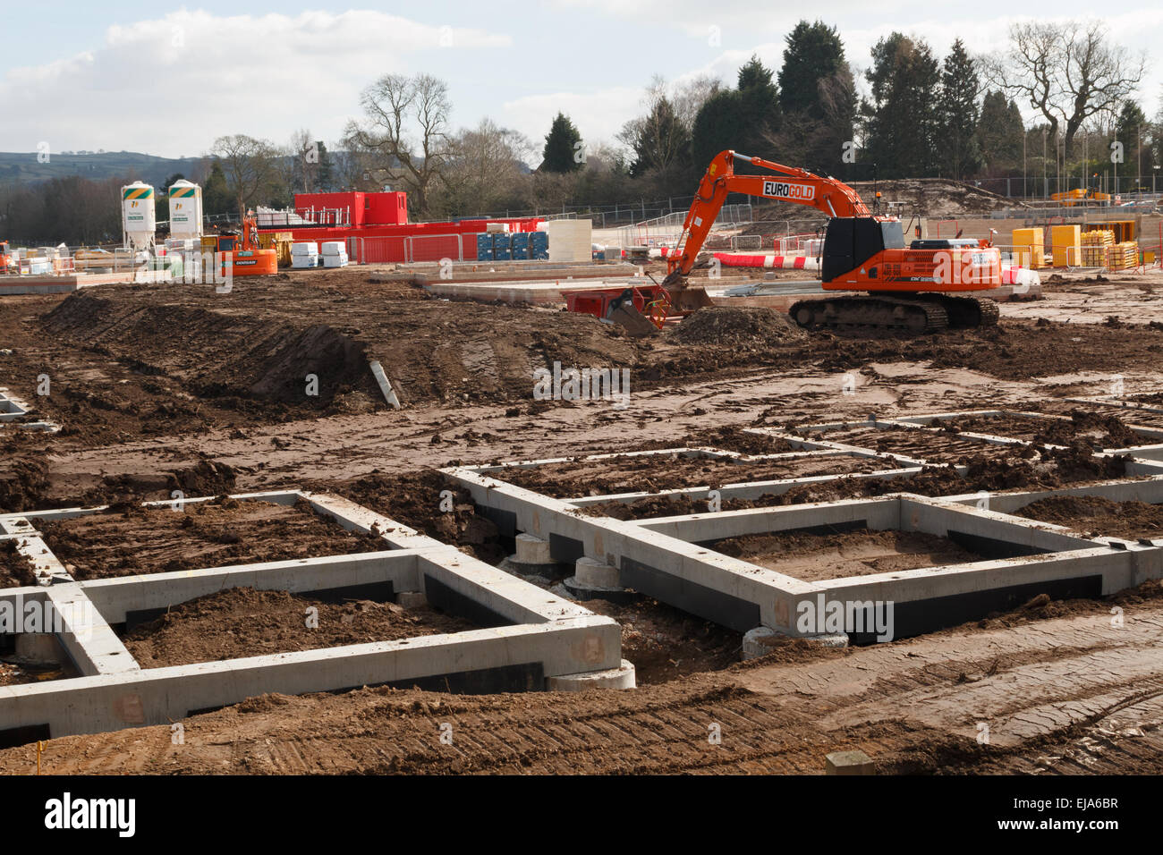 Residential construction site with the concrete foundations of rural starter homes.  Digger and mud. Stock Photo