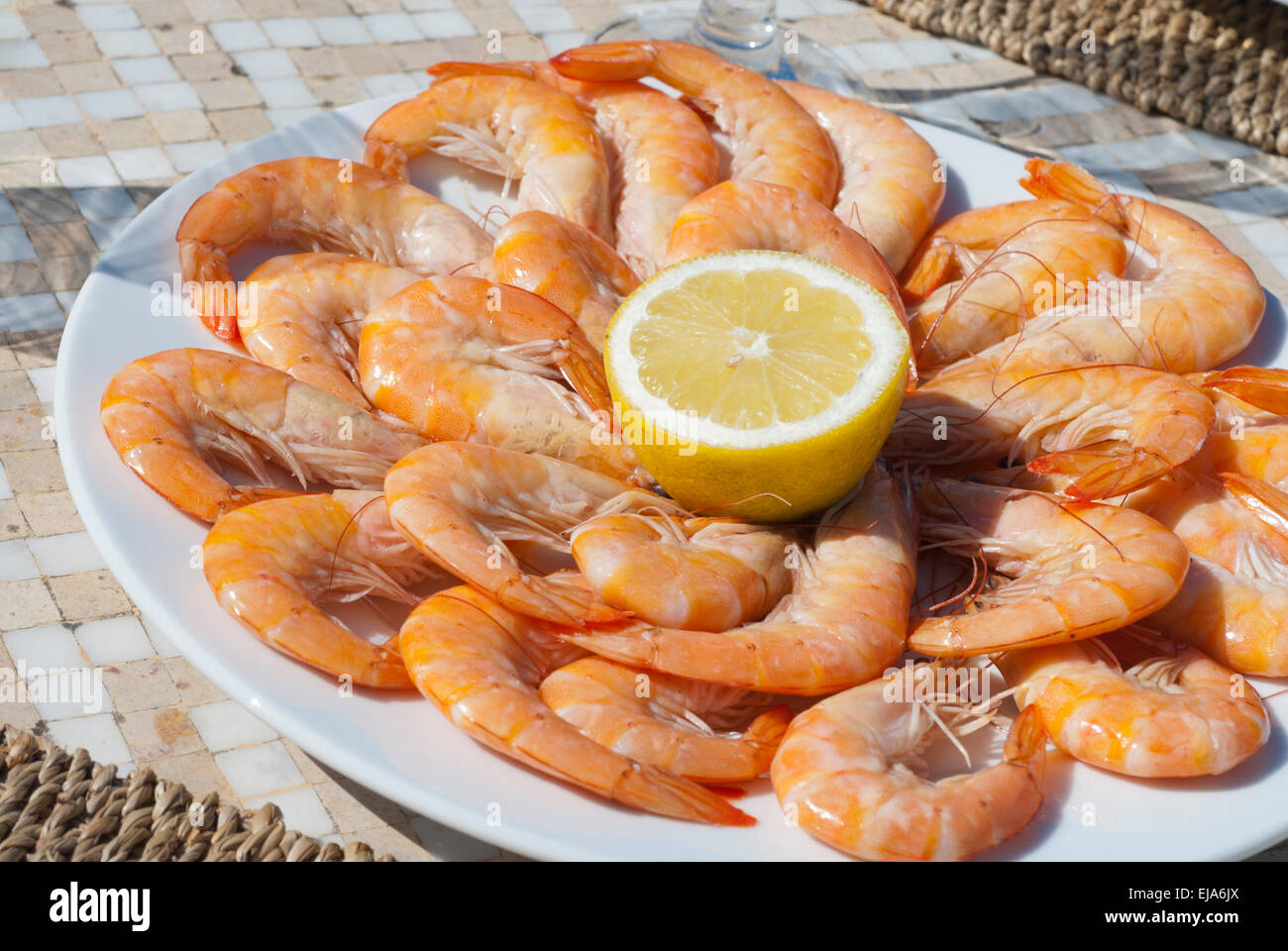 Plate of Prawns with Lemon juice on a round plate in the sunshine Stock Photo