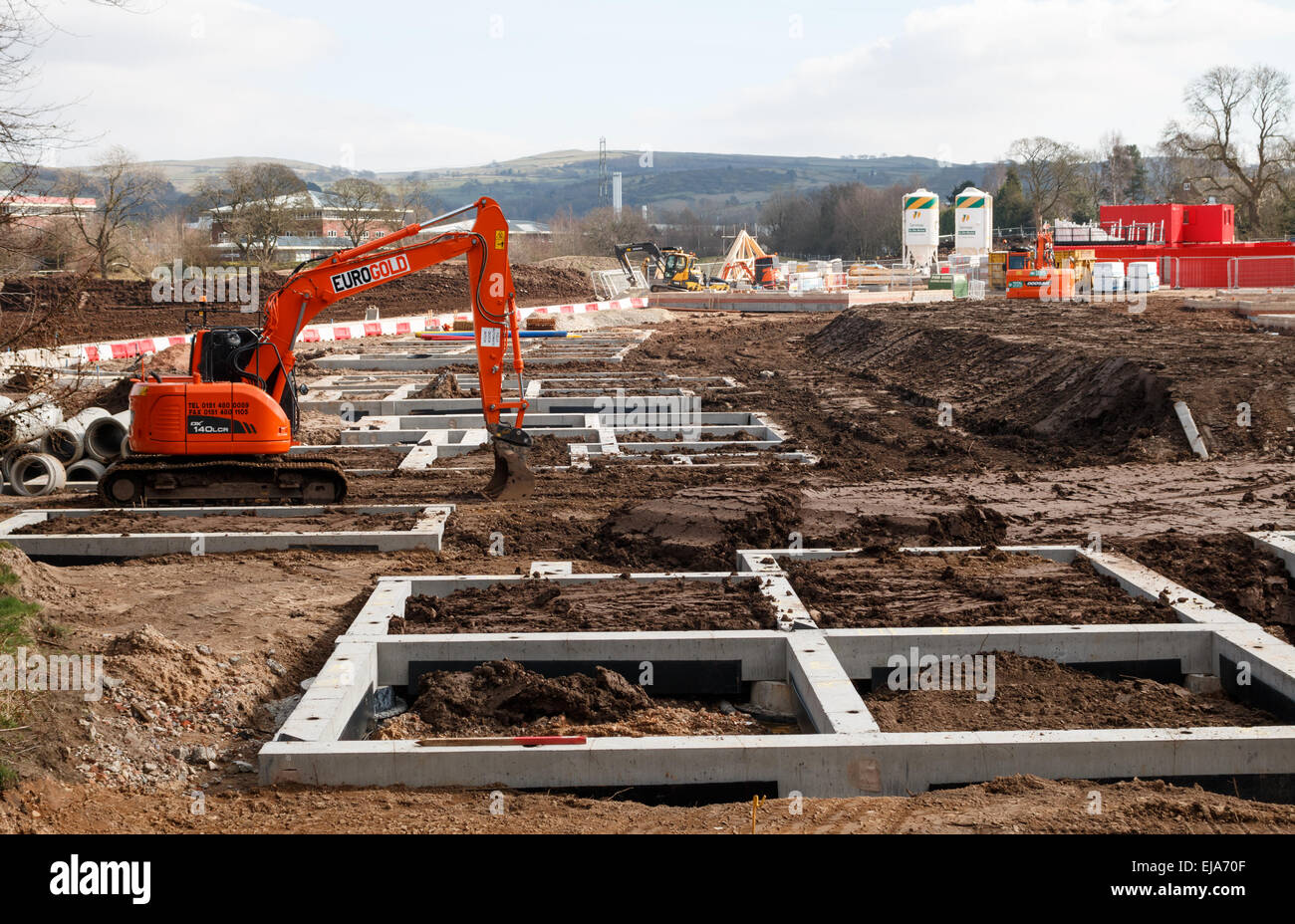 Residential construction site UK with the concrete foundations of rural starter affordable homes.  Digger and mud. Stock Photo