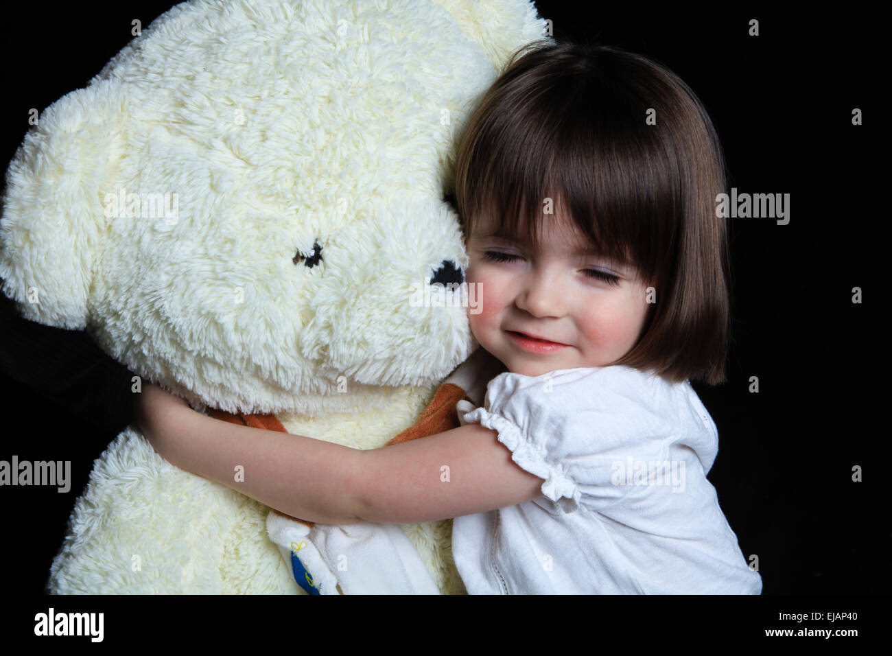 little girl with bear on a black background Stock Photo