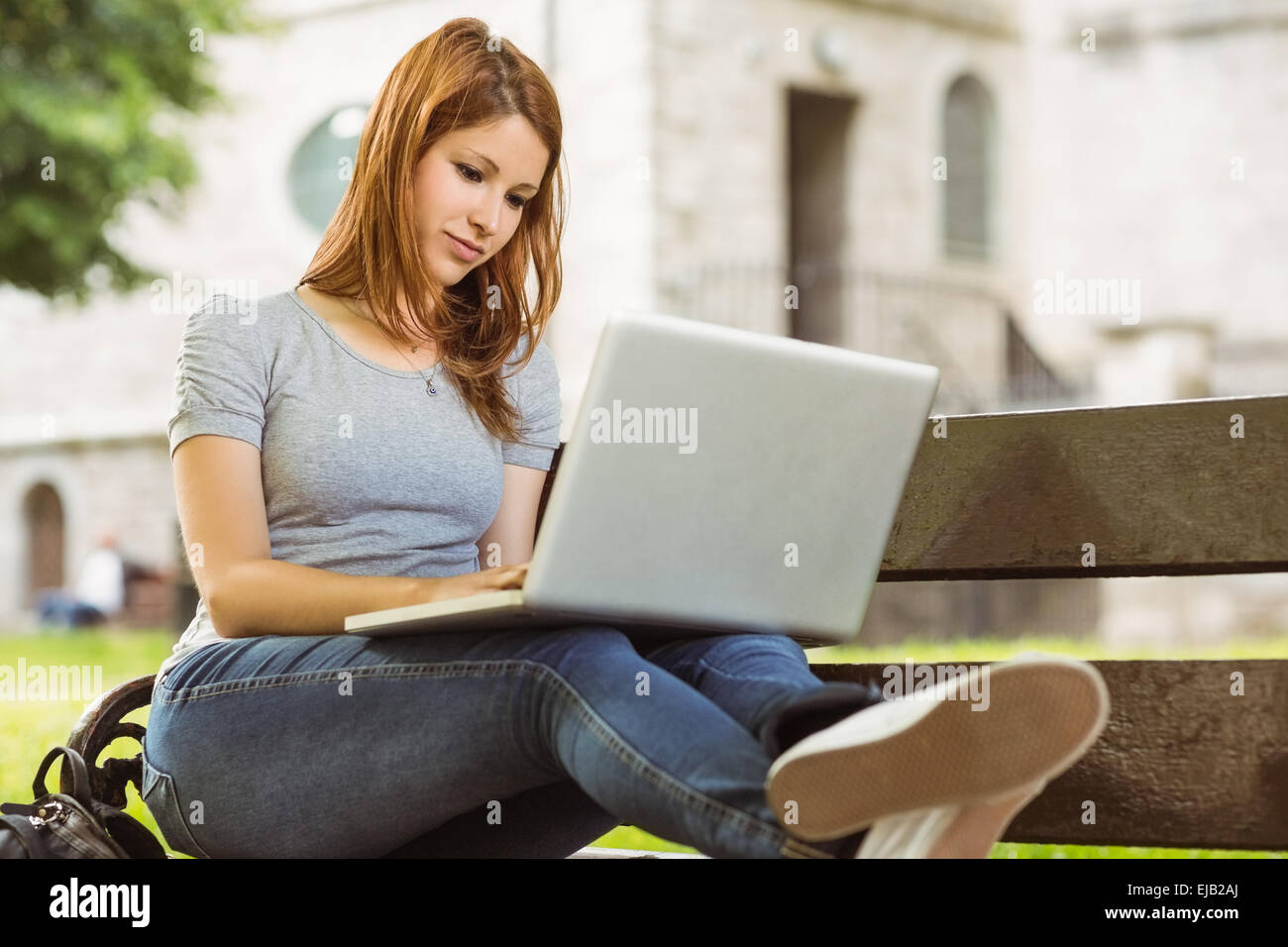 Happy girl sitting on bench using laptop Stock Photo - Alamy