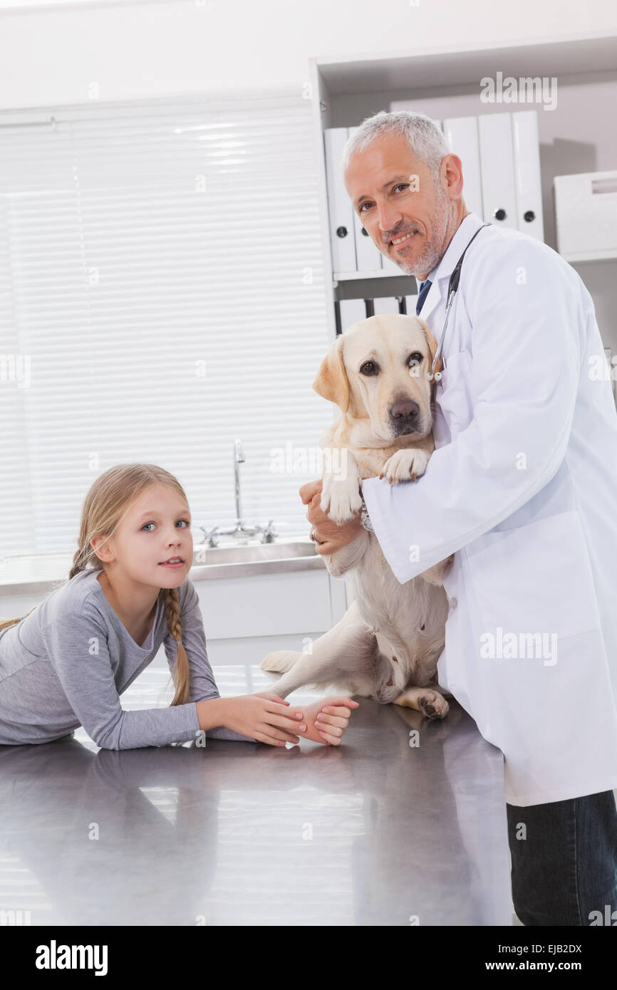 Smiling vet examining a dog with its owner Stock Photo - Alamy