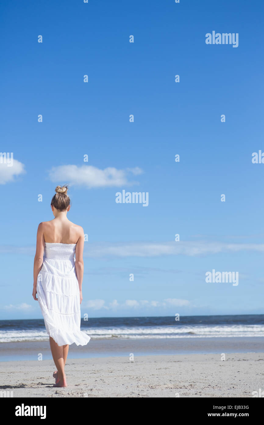 Blonde in white dress walking on the beach Stock Photo - Alamy