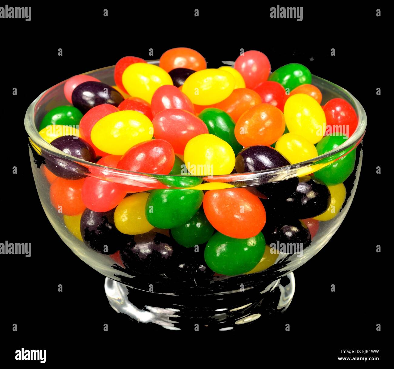 Fruit jelly beans in many colors in a glass bowl on a black background