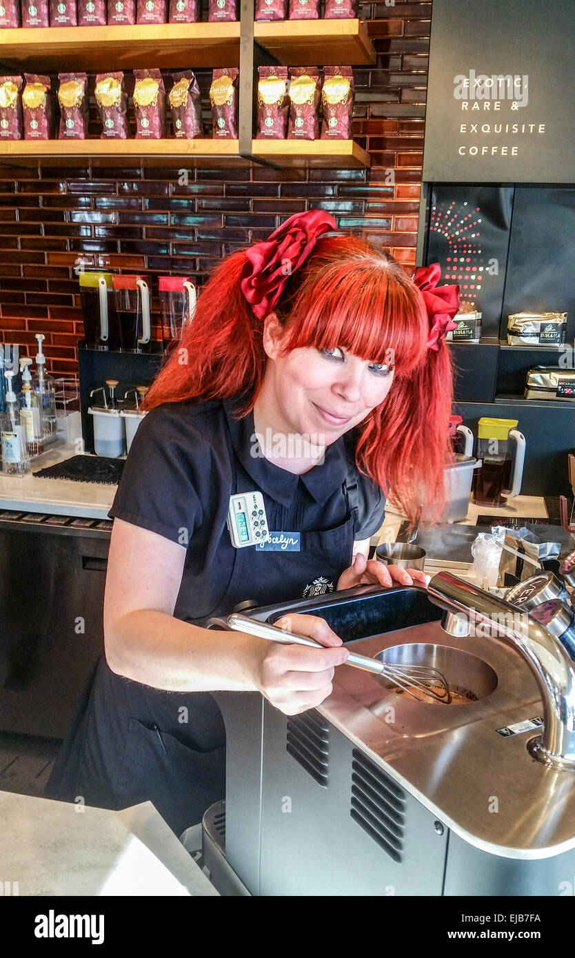Flame haired barista at a Starbucks whips up one of their high end gourmet coffees made with the expensive Clover machine Stock Photo