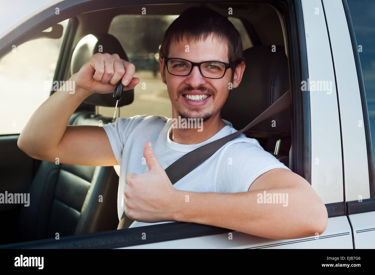 Young male european driver is holding new car key and showing thumb up Stock Photo