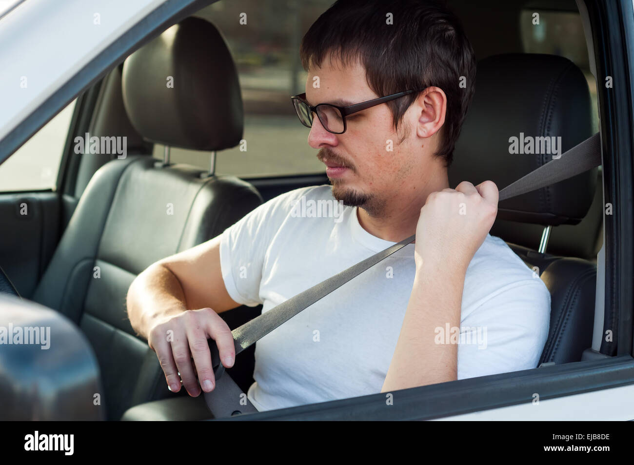 Male european driver is using seat belt in a car Stock Photo