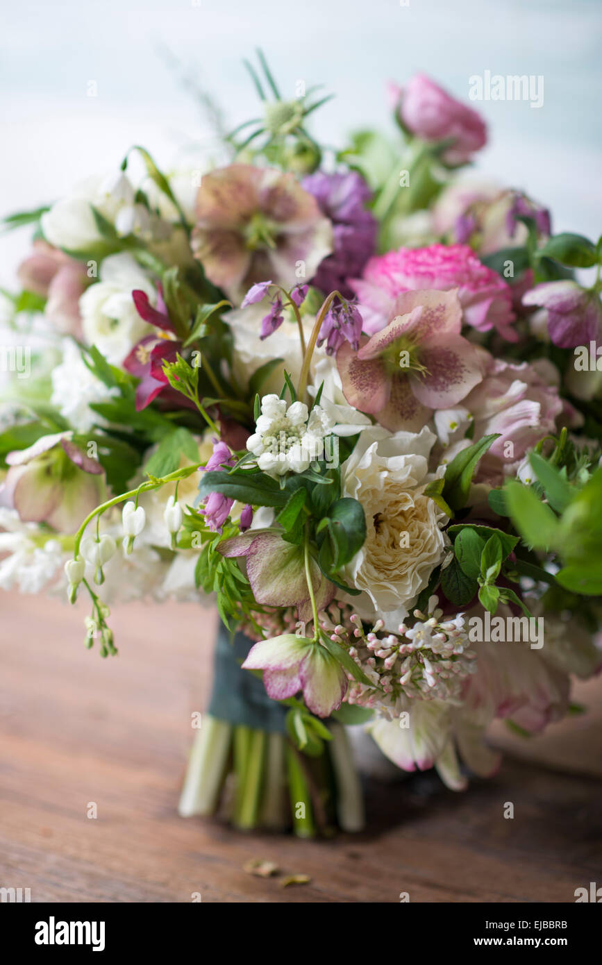 Abundant floral bouquet of spring blooming flowers including ranunculus hellebore parrot tulip tulipa and white Bleeding Heart Stock Photo