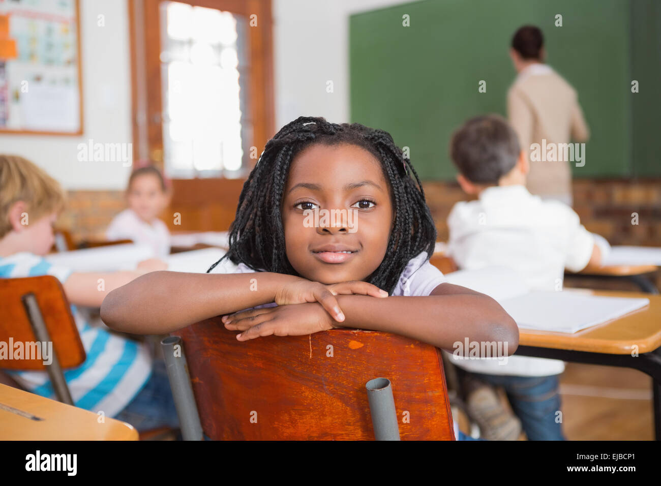 Smiling pupil sitting at her desk Stock Photo - Alamy