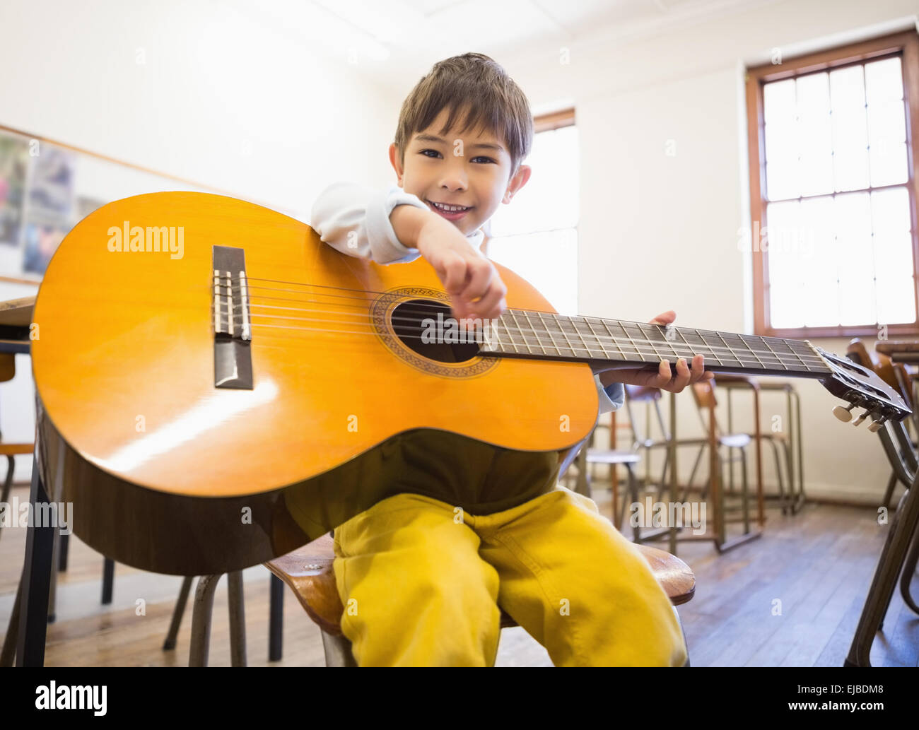Cute pupil playing guitar in classroom Stock Photo Alamy