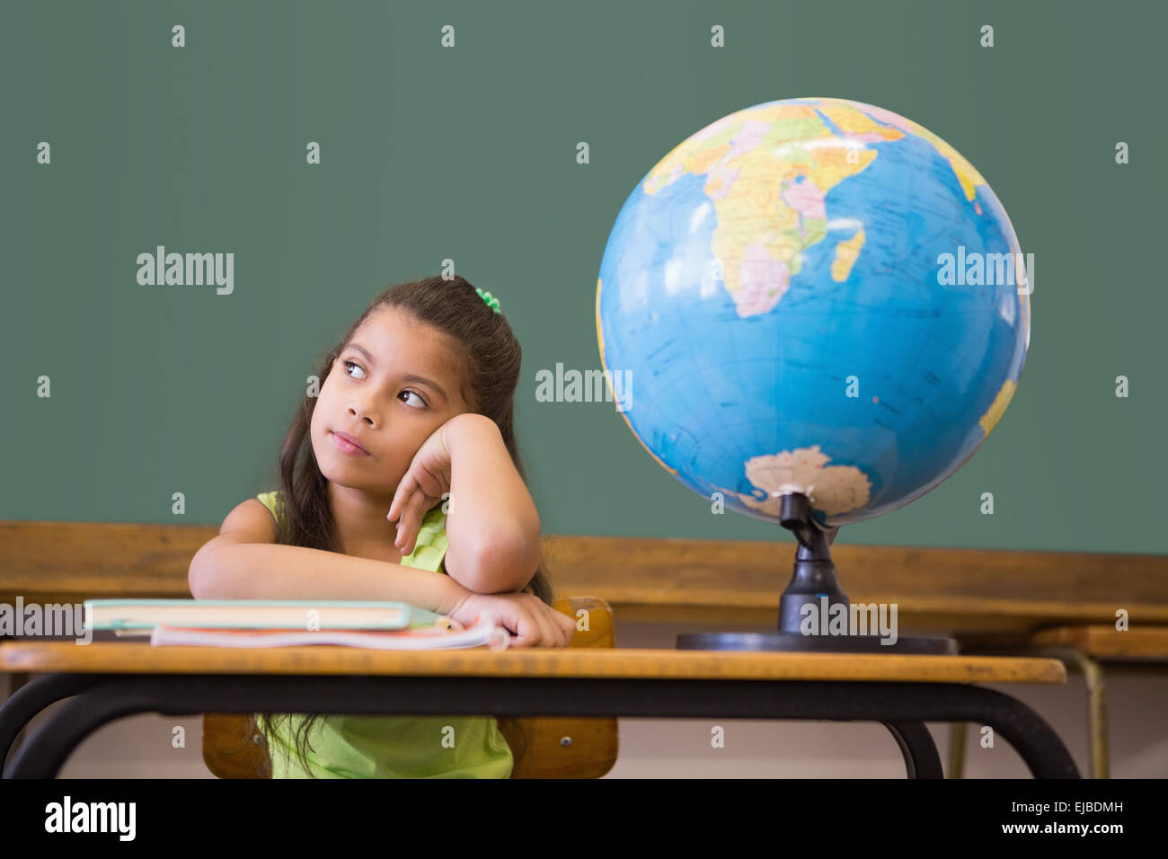Cute pupil thinking in classroom with globe Stock Photo - Alamy