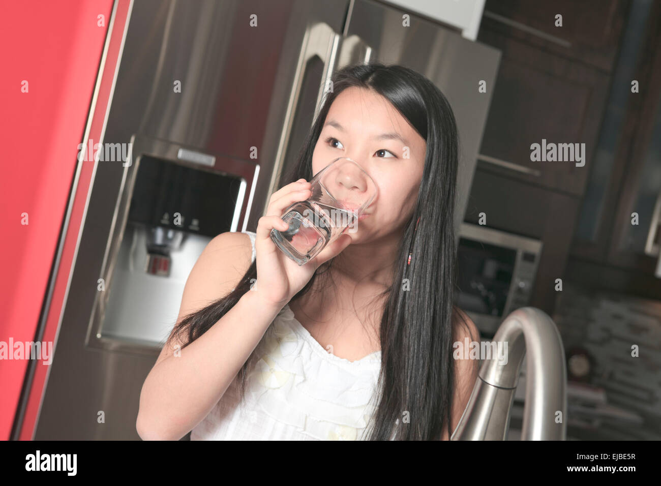 Teenager girl drinking water in the kitchen Stock Photo Alamy