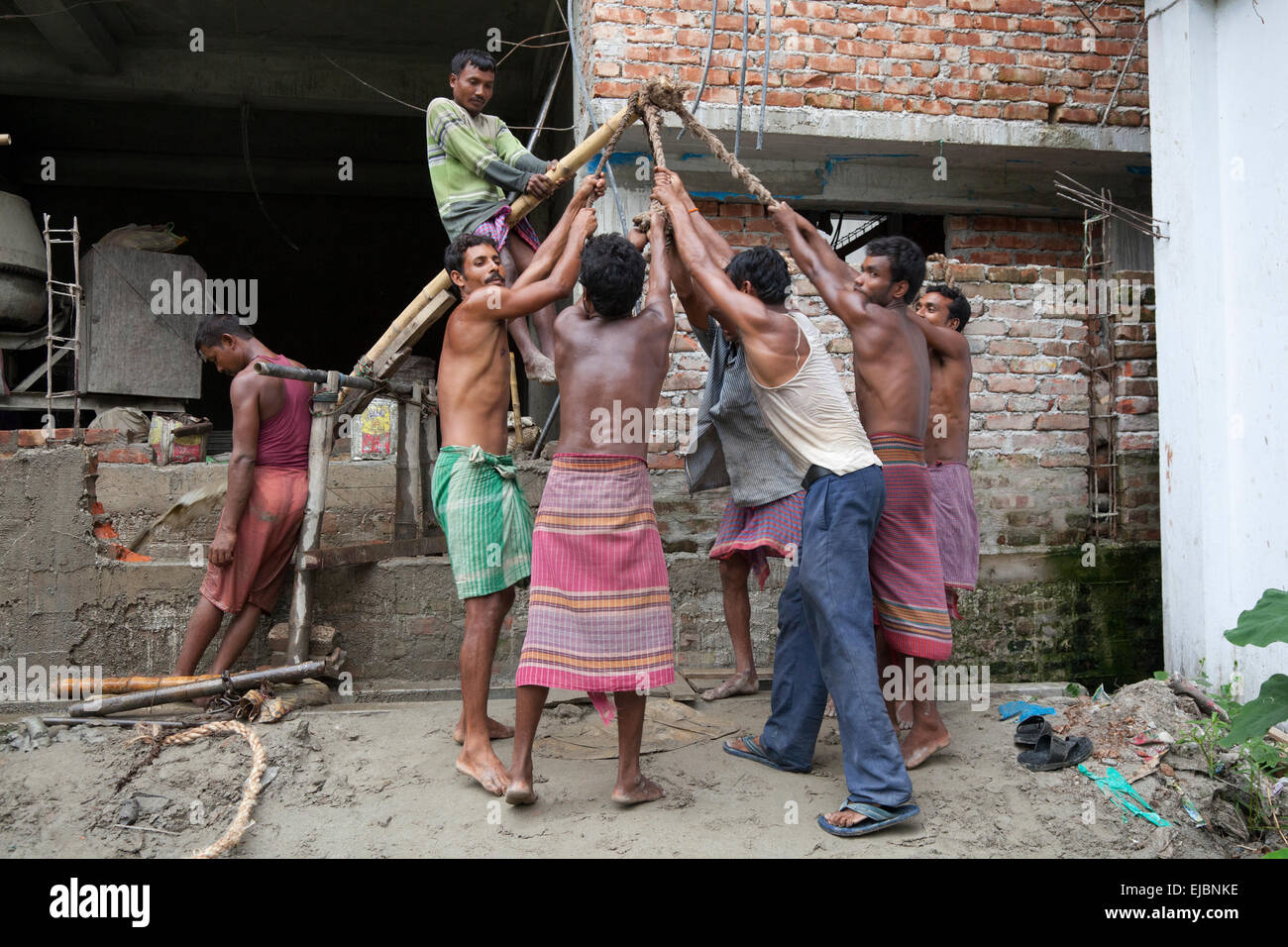 West Bengail laborers operating improvised bamboo pump to drain water from construction site in Cooch Behar, West Bengal Stock Photo