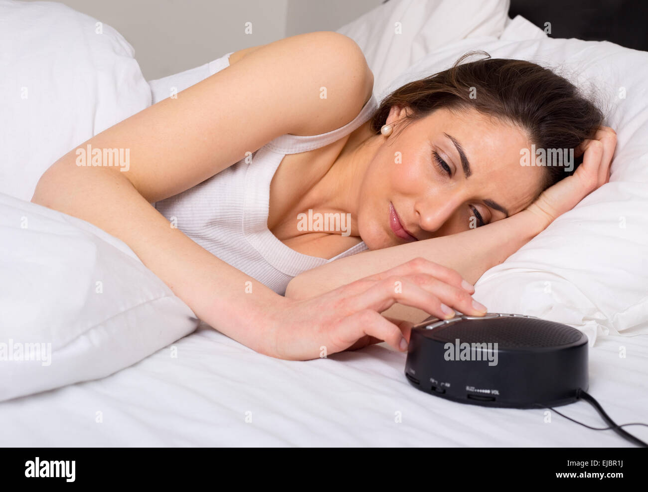 young woman turning off the alarm clock in the morning Stock Photo Alamy