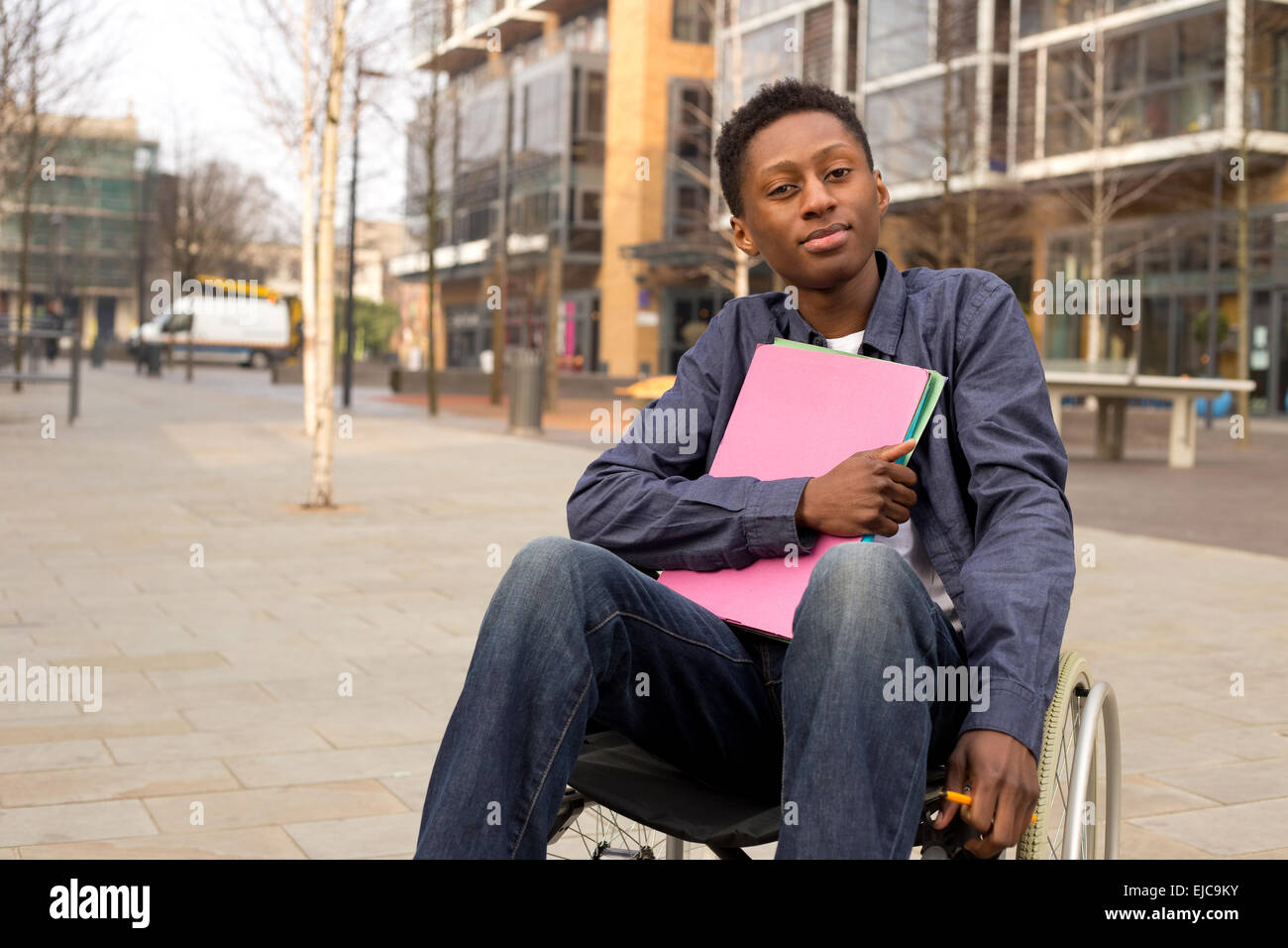 young disabled student sitting in a wheelchair  holding folders Stock Photo
