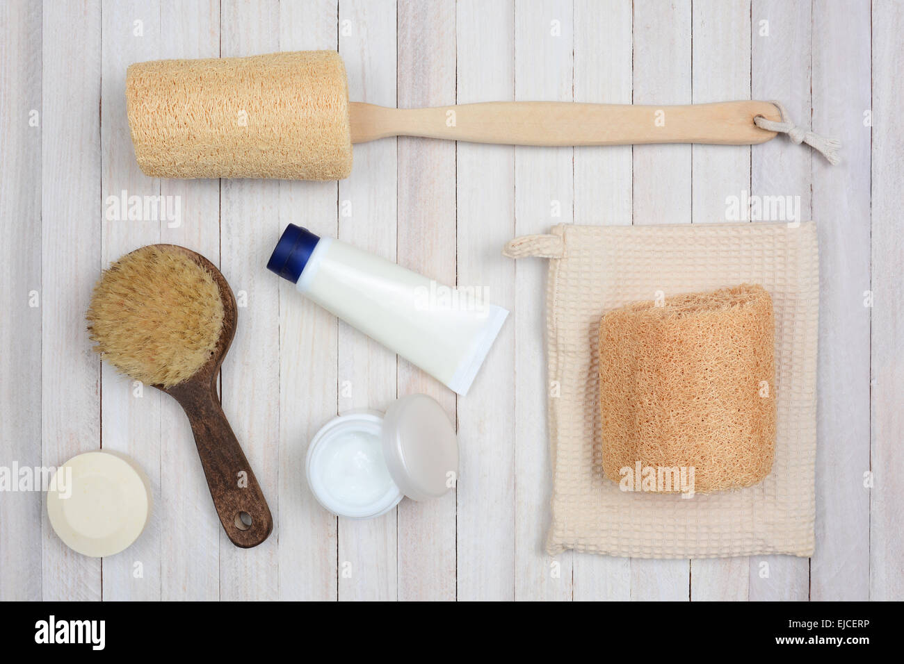 Bath and Spa accessories on a white rustic wood surface. Items include: luffa, brush, creams and soap. Stock Photo