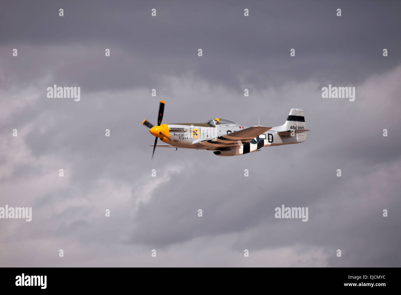 Fly by of P-51 Mustang air superiority fighter from vintage World War II. Nose art Section Eight. Flight with storm clouds. Stock Photo