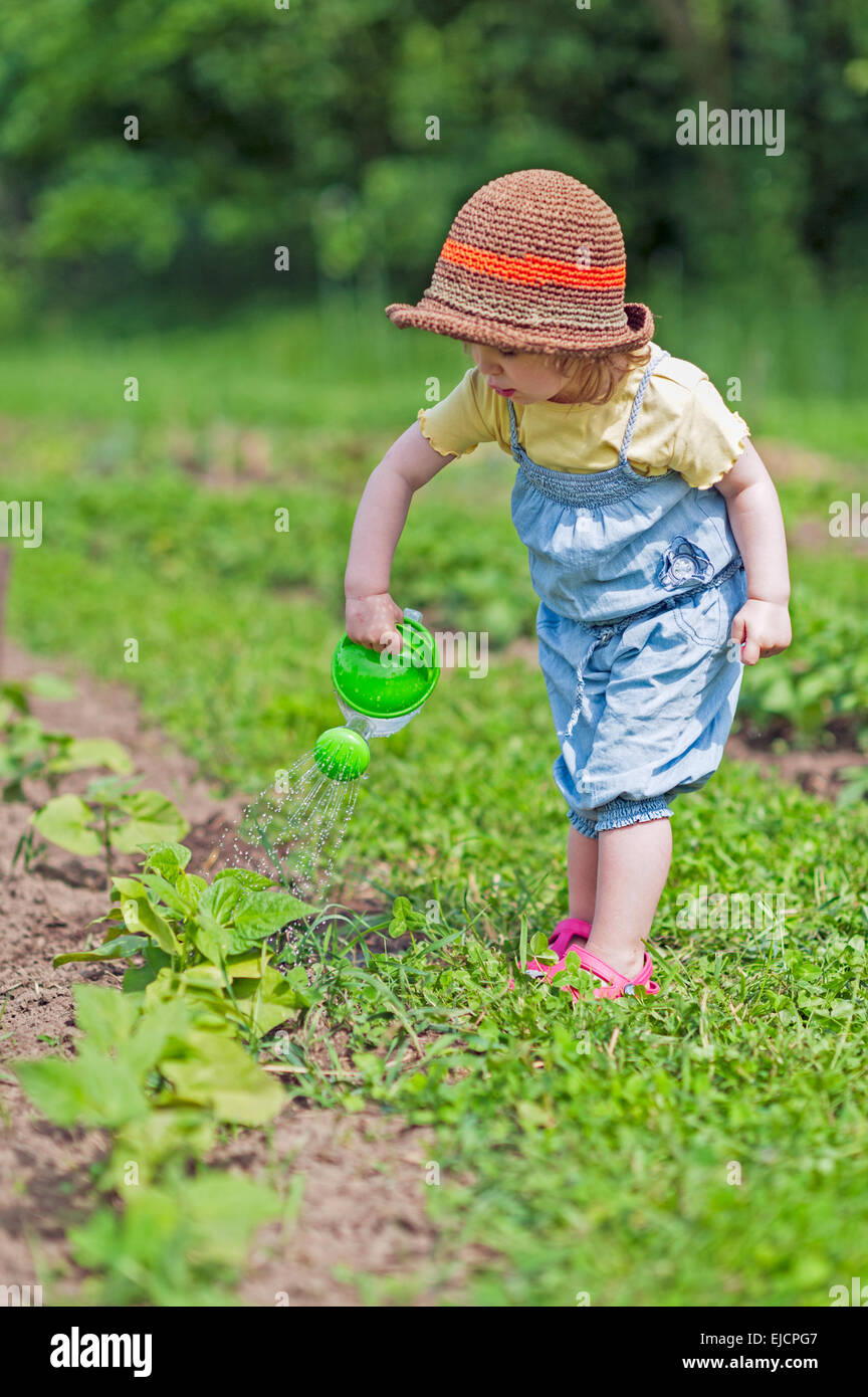 Girl with hat pouring vegetable Stock Photo