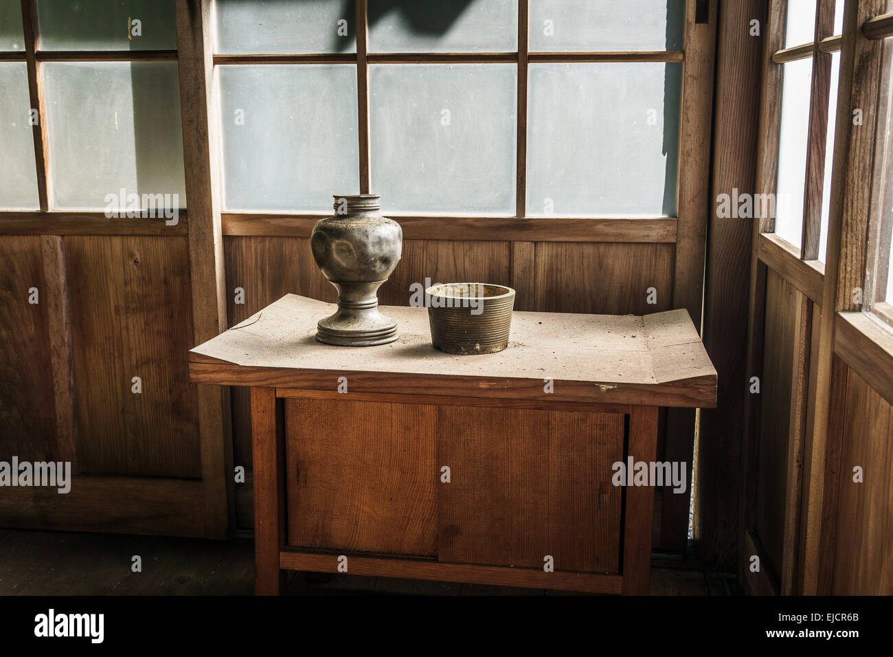 Two old vases on a wooden table in an abandoned wooden building on a sunny day Stock Photo