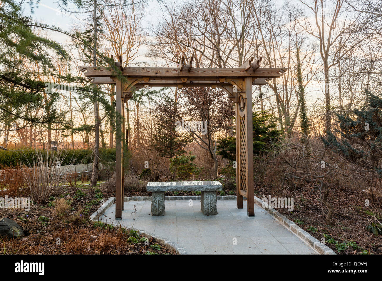Wooden arbor in forest with stone seat Stock Photo